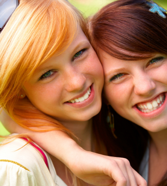 Closeup of two happy pretty teenagers embracing